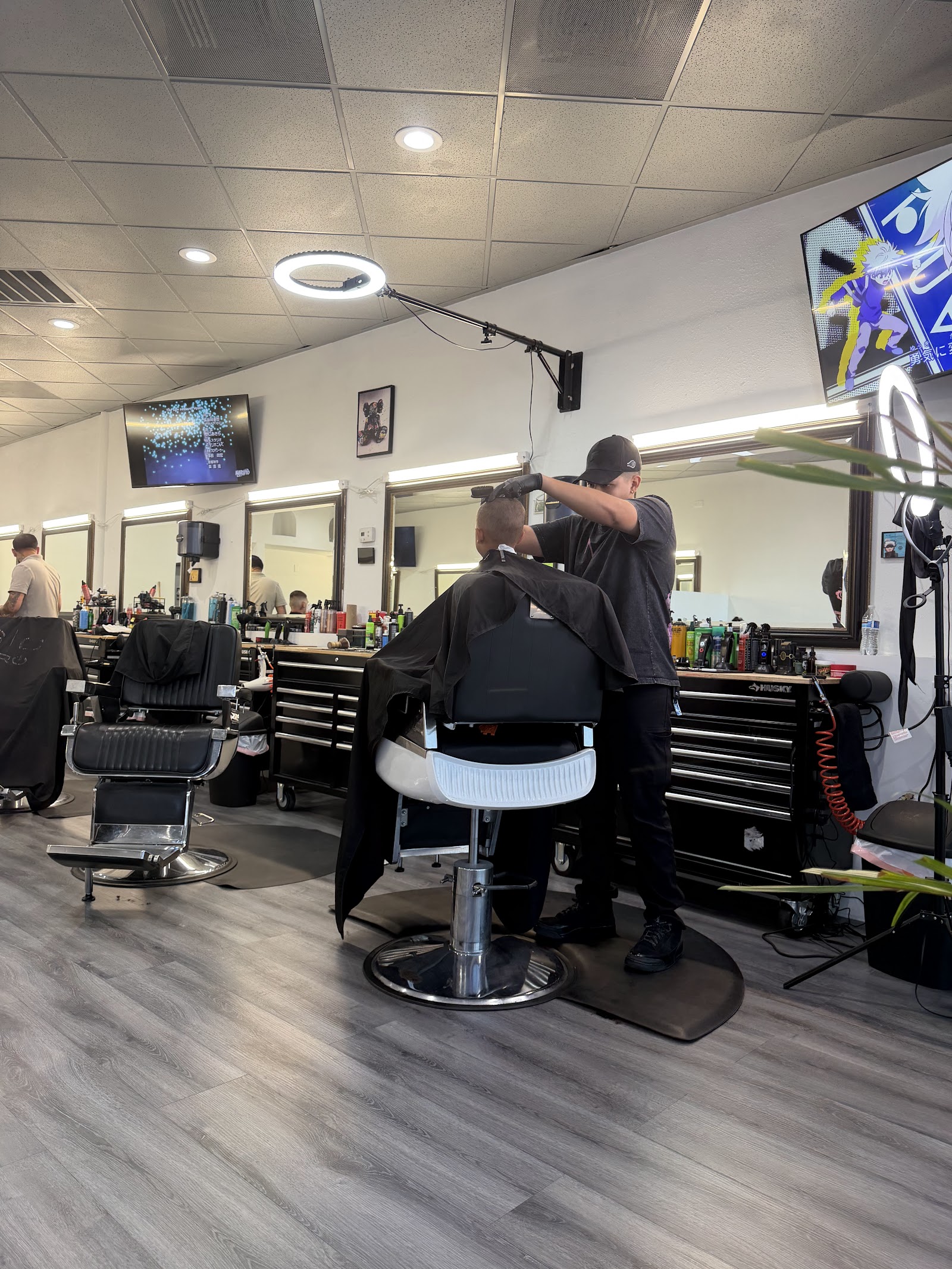 Barber cutting a client's hair under a ring light in a bright modern barbershop